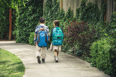 Mixed race brother and sister walking on sidewalk - BLEF07205