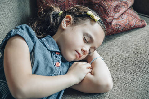 Gemischtrassiges Mädchen schläft auf Sofa, lizenzfreies Stockfoto