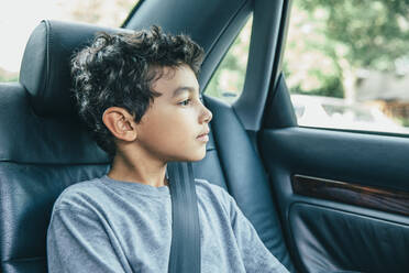 Gemischtrassiger Junge auf dem Rücksitz eines Autos - BLEF07224