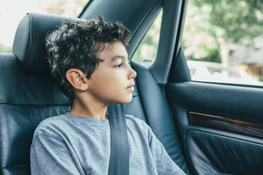 Mixed race boy sitting in car back seat - BLEF07224