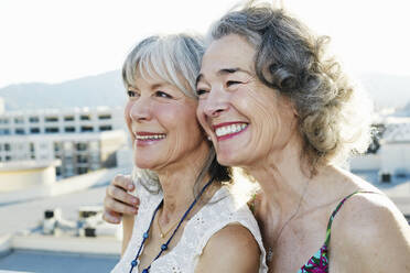 Gemeinsam lächelnde Frauen auf einem städtischen Dach - BLEF07238