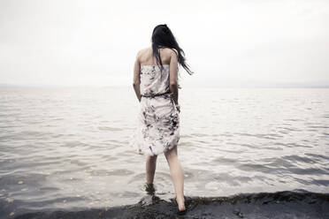 Kaukasische Frau watet am Strand im Wasser - BLEF07261