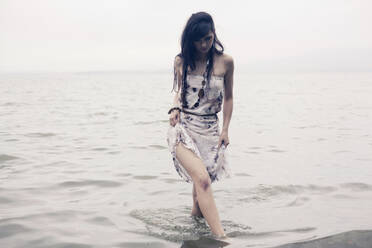 Kaukasische Frau watet am Strand im Wasser - BLEF07262