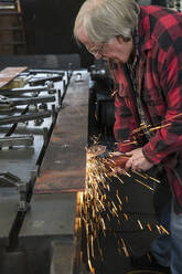 Kaukasischer Mann schleift Metall in einer Metallwerkstatt - BLEF07278