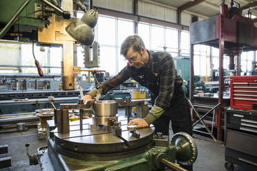 Kaukasischer Mann bei der Arbeit mit Maschinen in einer Metallwerkstatt - BLEF07280