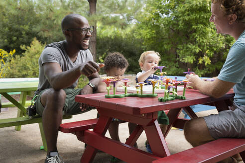 Fathers and toddler sons playing at picnic table - BLEF07375