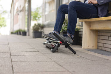 Businessman with folded E-Scooter on pavement, partial view - JOSF03283