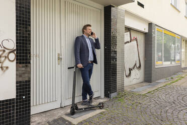 Geschäftsmann mit E-Scooter beim Telefonieren - JOSF03284