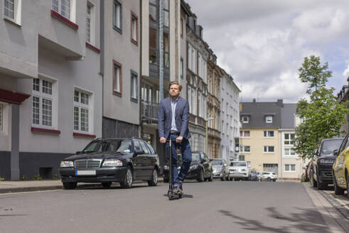 Businessman using E-Scooter in the city - JOSF03287