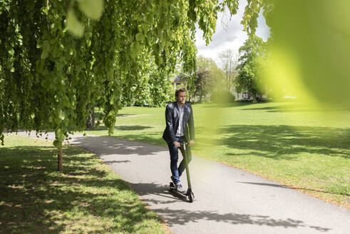 Geschäftsmann mit E-Scooter in einem Park - JOSF03293