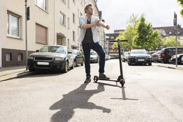 Mann steht mit E-Scooter auf der Straße - JOSF03314