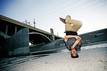 Gemischtrassiger Mann beim Breakdance unter einer Überführung - BLEF07400