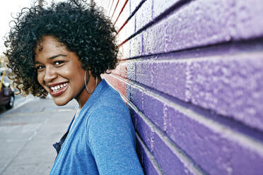 Mixed race woman standing by colorful wall - BLEF07443