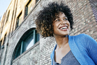 Mixed race woman smiling below urban building - BLEF07444