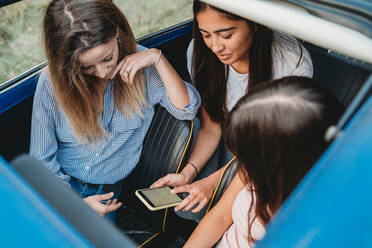 Friends using smartphone inside car - CUF51416