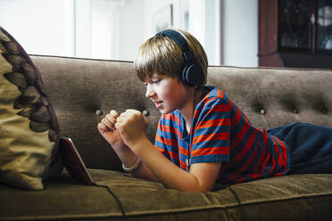 Caucasian boy using digital tablet on sofa - BLEF07538