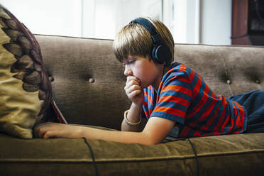 Caucasian boy using digital tablet on sofa - BLEF07539