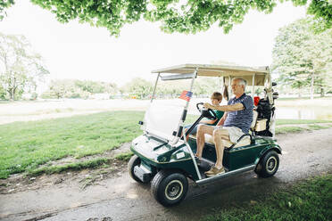 Kaukasischer Großvater und Enkel fahren Golfwagen auf dem Platz - BLEF07549