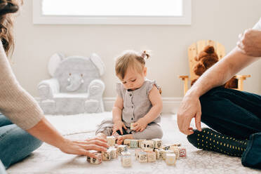 Mutter und Vater auf dem Boden des Kinderzimmers mit ihrer kleinen Tochter, die mit Bauklötzen spielt, Ausschnitt - ISF21481