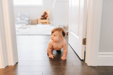 Baby girl crawling through nursery doorway - ISF21483