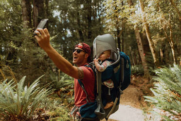 Father with baby taking selfie in forest, Queenstown, Canterbury, New Zealand - ISF21509