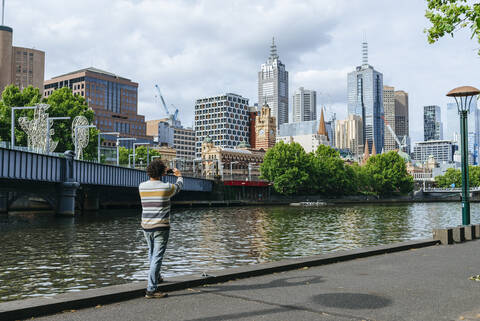 Mann fotografiert das Stadtbild von Melbourne mit dem Fluss Yarra, Victoria, Australien, lizenzfreies Stockfoto