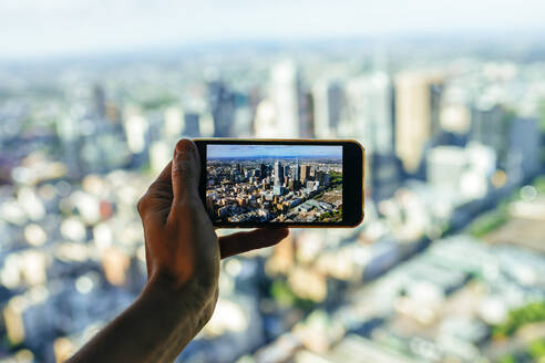 Close-up of man taking picture of the cityscape of Melbourne, Victoria, Australia - KIJF02495