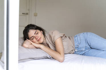 Lächelnde junge Frau auf dem Bett liegend mit geschlossenen Augen - AFVF03304