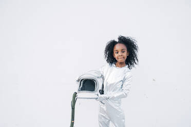 Portrait of little girl wearing space suit in front of white background - JCMF00063