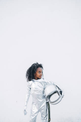 Little girl wearing space suit in front of white background looking around stock photo