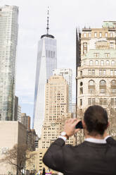 Rückansicht eines Mannes, der mit einem Smartphone Fotos macht, New York City, USA - MFRF01306