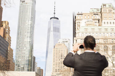 Rückansicht eines Mannes, der mit einem Smartphone Fotos macht, New York City, USA - MFRF01307