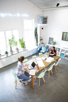 Zwei Frauen arbeiten am Tisch in einem modernen Büro - FKF03364