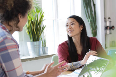 Two women talking at table in office - FKF03367