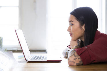 Frau mit Laptop am Tisch im Büro - FKF03392