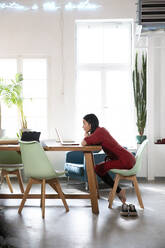 Frau mit Laptop am Tisch in einem modernen Büro - FKF03394
