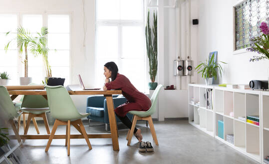 Frau mit Laptop am Tisch in einem modernen Büro - FKF03395