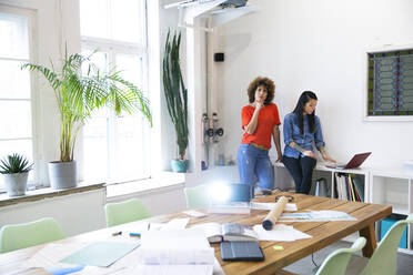 Two women in modern office with video projector on table - FKF03415