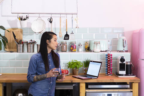 Frau mit Laptop in Büroküche, lizenzfreies Stockfoto
