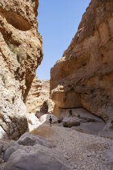 Mann geht durch Felsen, Wadi Bani Khalid, Oman - WWF05126