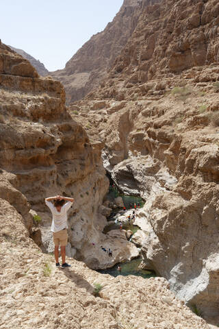 Mann genießt die Aussicht über Wadi Shab, Oman, lizenzfreies Stockfoto