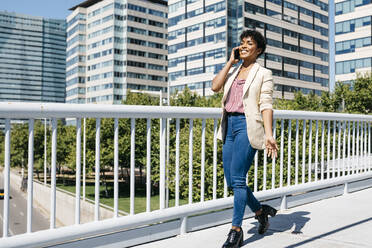 Businesswoman using smartphone, office buildings in the background - JRFF03290