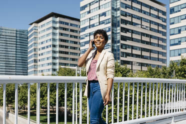 Businesswoman using smartphone, office buildings in the background - JRFF03291