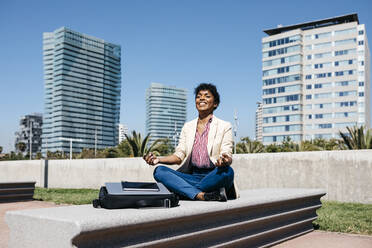 Geschäftsfrau sitzt auf einer Bank und meditiert - JRFF03296