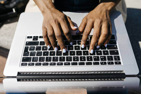 Geschäftsfrau, die auf einer Bank sitzt und mit dem Laptop tippt, lizenzfreies Stockfoto