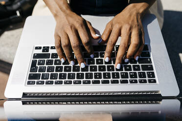 Businesswoman sitting on bench and using laptop finger typing - JRFF03308