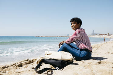 Frau sitzt am Strand und genießt die Sonne nach der Arbeit - JRFF03316