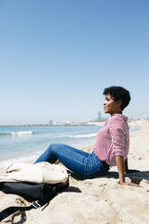 Frau sitzt am Sandstrand und genießt die Sonne nach der Arbeit - JRFF03318