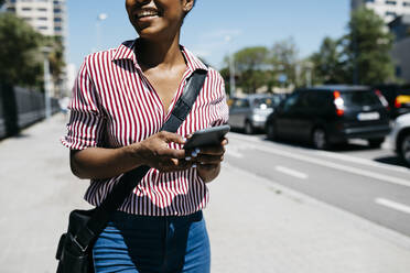 Woman using smartphone while walking in the city - JRFF03327