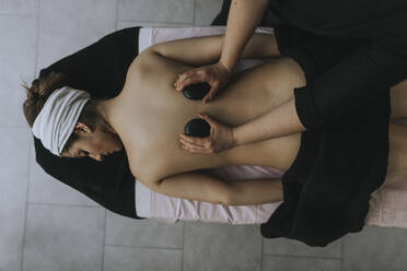 Frau liegt auf dem Bauch und genießt eine Wellness-Behandlung auf dem Rücken im Wellness-Center - OCAF00412